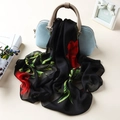 Elegant black silk scarf with red rose pattern draped over a light blue handbag - Rose Black