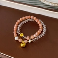 Detailed macro of layered orange moonstone and crystal beaded bracelets with gold charms - 14# Gold Coin Bag