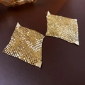 Foto macro de pendientes dorados con borlas de circonio y detalles de malla geométrica - Dorado