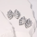 Elegantes pendientes de lazo 3D en acero inoxidable sobre fondo de piedra minimalista - Color Acero