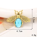 Macro detail of vintage gold bee charm with blue gemstone and dimension markings - Gold/Blue Gem Bee