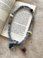 Detail einer böhmischen Baumwollkordelkette mit bunten Harzperlen auf einem Buch - Halskette-Hellblau