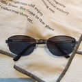 Close-up of retro oval metal frame glasses with black lenses on vintage beige canvas - Gold Grey