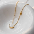Golden sea series necklace with white shell pendant placed on a white ceramic dish - White Shell Heart Style (81123)