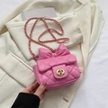 Mini bolso rosa bandolera con lazo y cadena dorada sobre un blazer beige - Rosa