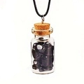 Detailed close-up of a glass wish bottle pendant with black obsidian stones and a cork top - Black Agate
