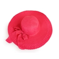 Close-up of woven straw sun hat texture with a large magenta satin ribbon bow - Watermelon red