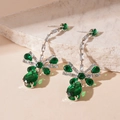 Dettaglio di orecchini a fiocco in zircone verde su sfondo di pietra beige materico - Perno in argento 925 / Orecchini / Perno in argento-Orecchini verdi