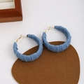 Close-up of blue denim hoop earrings with white speckles on a brown suede pad - Light Blue