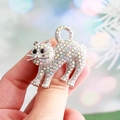 Spilla gatto scintillante con strass colorati tenuta in mano per mostrare la misura - Gatto Argento Strass Colorato / Bianco