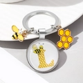 Detail of silver bee keychain featuring letter L dome charm, enamel bee, and honeycomb pendant - Letter L