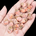 Pink and orange natural raw stone pendants with gold-plated caps held in palm - Sunstone