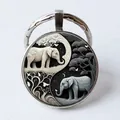 Silver-rimmed glass keychain with black and white yin yang elephant art illustration - Yin Yang Elephants/Butterfly