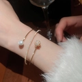 Detailed macro view of a three-layer gold bracelet with shimmering zircon and pearl inlay - Gold-White Flower (HB4661)