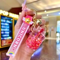 Close-up of pink unicorn keychain featuring liquid glitter bottle and rainbow cloud charms - Red Luminous Bubble Bead Gas Tank