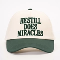 Dettaglio del ricamo HE STILL DOES MIRACLES su un cappellino da baseball bicolore - Crema/Verde Scuro