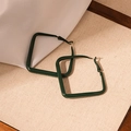Dettaglio macro di orecchini geometrici quadrati verde scuro su tessuto beige - Verde Scuro