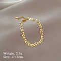 Dettaglio di un bracciale in acciaio inossidabile dorato a forma di foglia su raso champagne - Design a Foglia / Oro