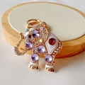 Close-up of golden elephant keychain with white enamel and purple crystal rhinestones - Purple