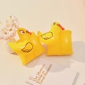 Pair of yellow inflatable duck swimming armbands for kids on a light wooden table - Chick Arm Bands