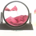 Pink moving sand art in black circular frame with a layered mountain texture effect - 12 Inch Stand Pink