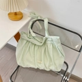 Détail du sac en toile plissée vert clair avec nœud et étiquette sur une chaise claire - Ramie Vert Menthe