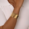 Close-up of golden wide textured metal bangle on model wearing a white ribbed polo shirt - Gold Wave Narrow Style (B-551G)