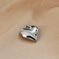 Dettaglio di un ciondolo a cuore in argento lucido su tessuto beige strutturato - Stile Cuore (17#)