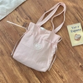 Close-up of pink fabric tote bag featuring heart lace patches and ribbon bow details - Pink