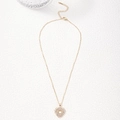 Collier avec pendentif cœur doré et cristaux de zircon blancs sur fond blanc avec texture - Zircone Blanche