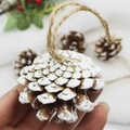 Close-up of a hand holding a natural pinecone ornament with white painted snow and hemp rope - With Rope (Brushed White 4-5cm)