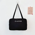 Detail der minimalistischen schwarzen Canvas-Tasche mit weißem SOZAKKA-Stick an weißer Wand - Minimalistischer Stickerei-Stil (Mit Lamm-Anhänger) / Schwarz