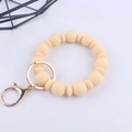 Dettaglio del portachiavi a bracciale in silicone crema con moschettone dorato su sfondo bianco - Beige