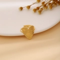 Goldener Herzring mit gehämmerter Textur auf weißer Keramik mit Trockenblumen Hintergrund - Herz Gehämmert Stil