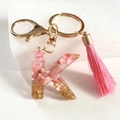 Pink resin letter K keychain with gold foil flakes and a matching pink silk tassel charm - Letter K