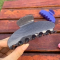 Nahaufnahme einer anthrazitfarbenen Glitzer-Haarklammer aus Acetat in der Hand gehalten - Sieben-Zähne-Klammer / Space Grau Glitzer