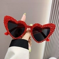 Oversized heart shaped sunglasses with red rhinestones and dark lenses held in hand - Red with Rhinestones