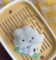 Detail view of a fluffy gray plush cloud charm with blue legs and a premium leather strap - Gray