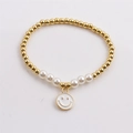Gold-plated beaded bracelet with white pearls and smiling face pendant on white background - White