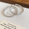 Gros plan de boucles d'oreilles créoles argentées avec texture sur fond de lin - Fer/Tige en Argent 925 / Argent-Diamètre 50mm