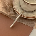 Detail of elegant gold metal hair clip with white pearls resting on a vintage ceramic cup - Pearl-Gold Bobby Pin