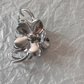 Detailed top view of a silver floral metal hair claw clip on white textured paper - Silver