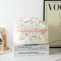 Detailed close-up of cream quilted cosmetic bag with pink bow pattern and top handle - Large White with Pink Bow