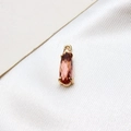 Macro view of water drop amber glass pendant with golden four-claw setting on white silk - Lotus Pink