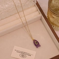 Detailaufnahme eines lila Fisch-Edelsteinanhängers mit Goldkette in Schmuckbox - Amethyst