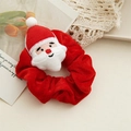 Close-up of red velvet Christmas scrunchie featuring a plush Santa Claus head detail - Santa Claus