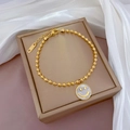 Detail van gouden kralenarmband met smile-hanger en verstelbare stalen verlengketting - Gouden Kraal Witte Parelmoer Smiley-stijl (K333 Witgoud)