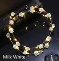 Detail of LED floral wreath with white roses and warm lights on vintage book background - Cream