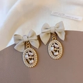 Franse vintage strik oorbellen met parelhangers op een elegante lederen textuur - Oorknopjes / Beige