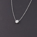 Gros plan d'un collier en acier inoxydable argenté avec un petit pendentif en forme de fleur - Acier